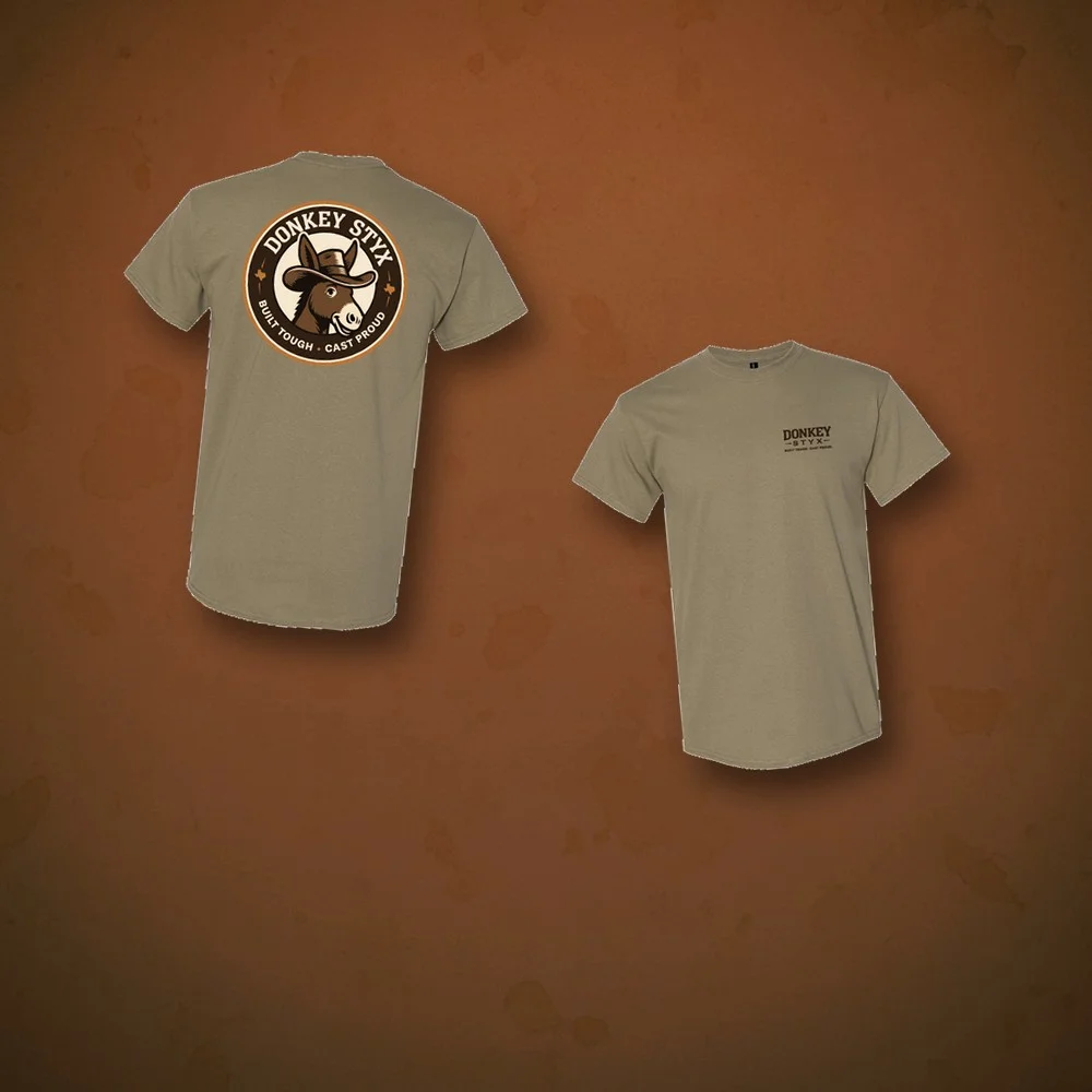 The real approved Donkey Styx tee art, front and back, on a rich branded surface, a merch moment